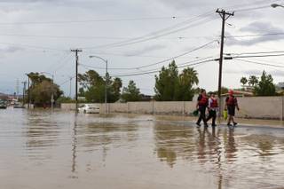 Las Vegas Firefighters escort a man out of the flooded intersection of E. Sahara Avenue and Winterwood Boulevard after his vehicle became stranded, Tuesday, Sept. 11, 2012.